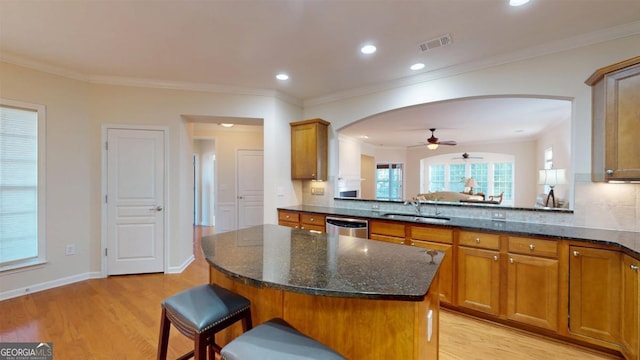 kitchen featuring sink, dark stone counters, a kitchen bar, and a center island