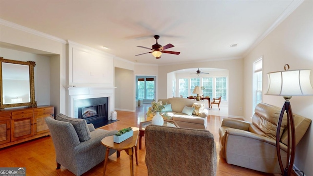 living room featuring light wood-type flooring, crown molding, and ceiling fan