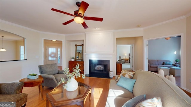 living room with light hardwood / wood-style floors, ceiling fan, ornamental molding, and a fireplace