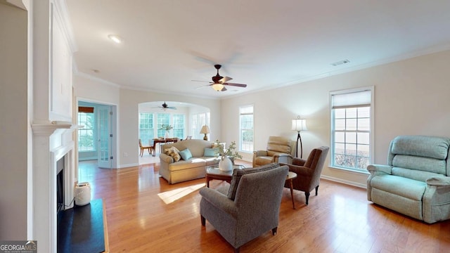 living room with light hardwood / wood-style flooring, a wealth of natural light, and ornamental molding