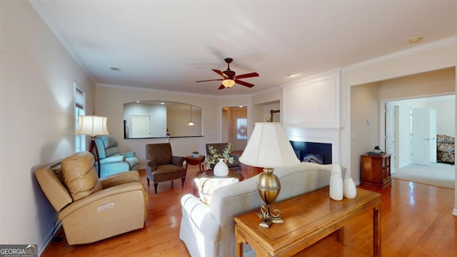 living room featuring light hardwood / wood-style flooring, ceiling fan, and ornamental molding