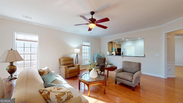 living room with ceiling fan, ornamental molding, and light hardwood / wood-style floors