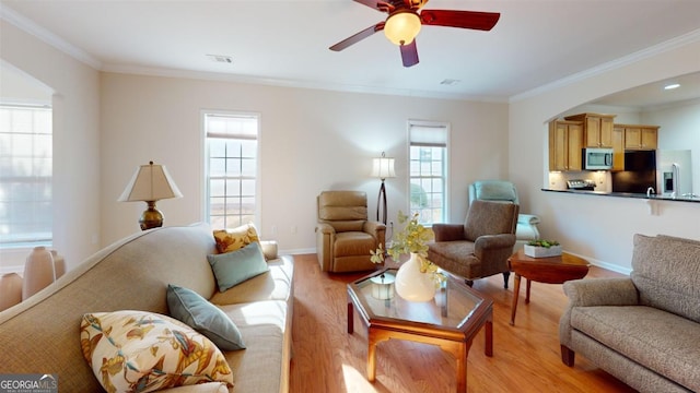 living room with light hardwood / wood-style floors, plenty of natural light, ceiling fan, and ornamental molding