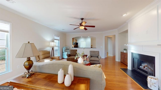 living room with ceiling fan, ornamental molding, plenty of natural light, and light hardwood / wood-style flooring