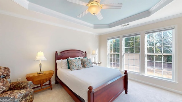 carpeted bedroom featuring a tray ceiling, ceiling fan, and crown molding