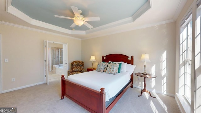 carpeted bedroom with connected bathroom, crown molding, a tray ceiling, and ceiling fan