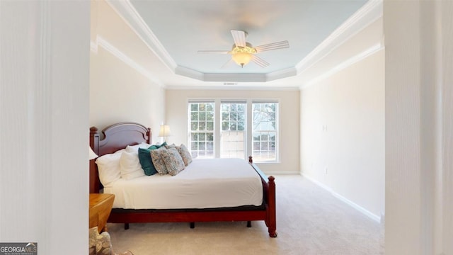 bedroom with a tray ceiling, ceiling fan, crown molding, and light colored carpet