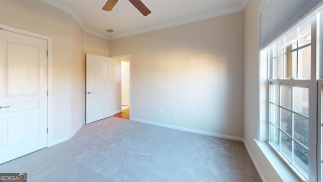 unfurnished bedroom featuring ceiling fan, ornamental molding, multiple windows, and light colored carpet