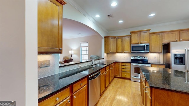 kitchen featuring dark stone countertops, appliances with stainless steel finishes, sink, and light hardwood / wood-style flooring