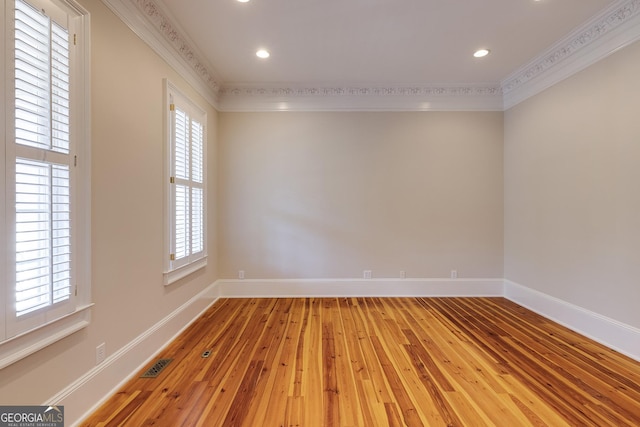 empty room featuring hardwood / wood-style floors, a wealth of natural light, and crown molding