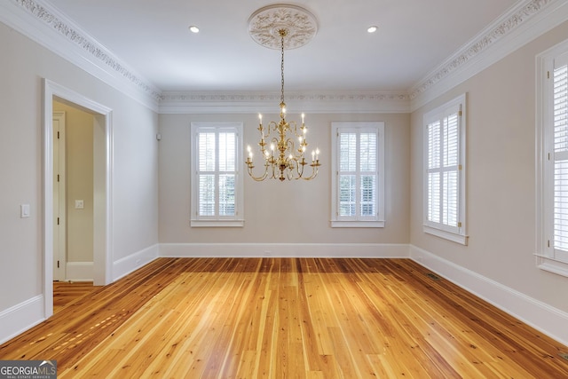 unfurnished dining area with crown molding, an inviting chandelier, and wood-type flooring