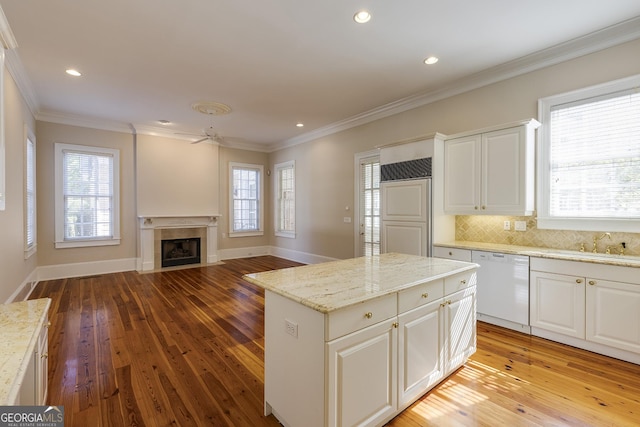 kitchen with light stone counters, white cabinetry, dishwasher, a kitchen island, and crown molding