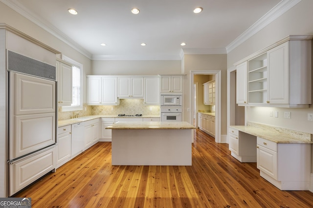 kitchen featuring built in appliances, white cabinetry, built in desk, and light stone counters