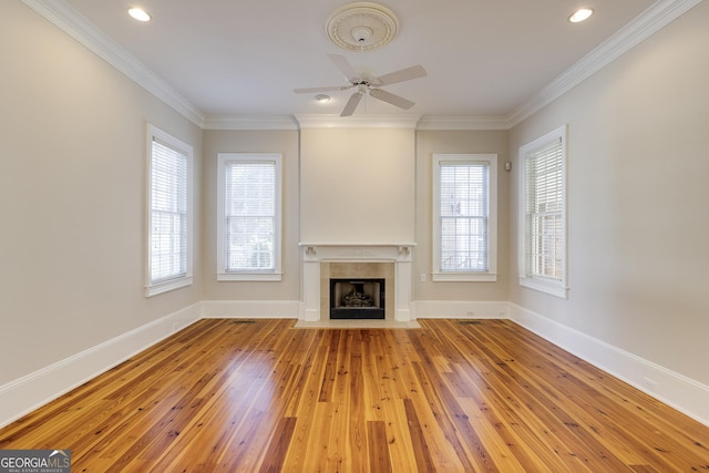 unfurnished living room with a fireplace, crown molding, ceiling fan, and light hardwood / wood-style flooring