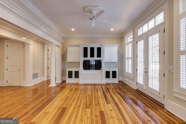 unfurnished living room with decorative columns, ceiling fan, crown molding, and light hardwood / wood-style floors