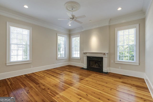 unfurnished living room with a fireplace, light hardwood / wood-style floors, crown molding, and a wealth of natural light