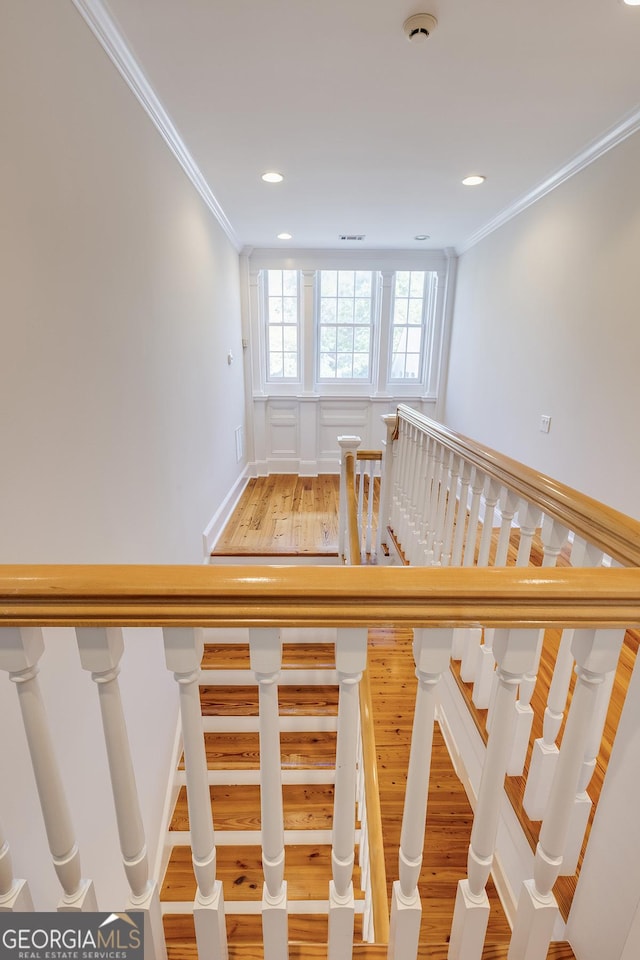 staircase featuring ornamental molding and hardwood / wood-style floors