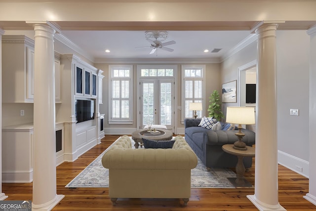 living room with ceiling fan, dark wood-type flooring, crown molding, and ornate columns