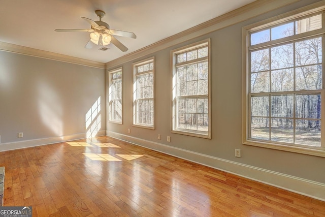 empty room with light wood-style floors, baseboards, visible vents, and ornamental molding