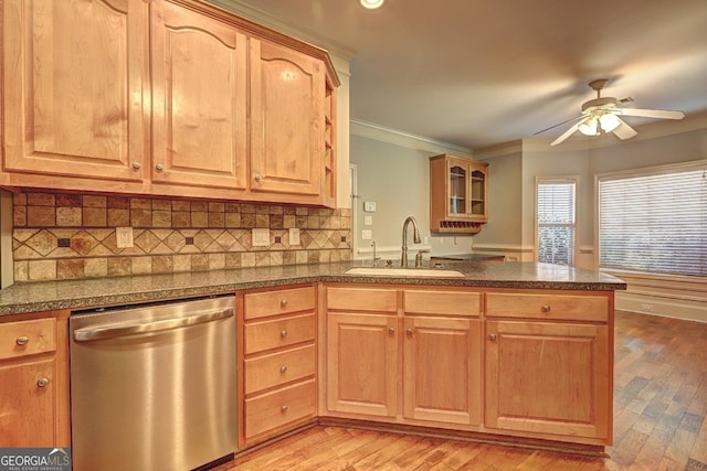 kitchen featuring a sink, ornamental molding, stainless steel dishwasher, dark countertops, and glass insert cabinets