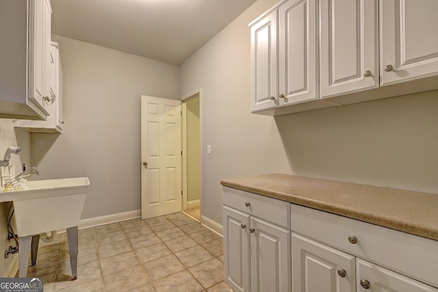 kitchen with light tile patterned floors, light countertops, white cabinetry, and baseboards