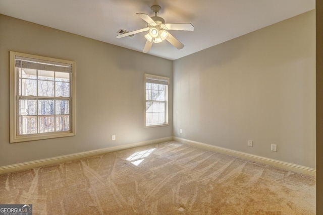 carpeted empty room with visible vents, ceiling fan, and baseboards