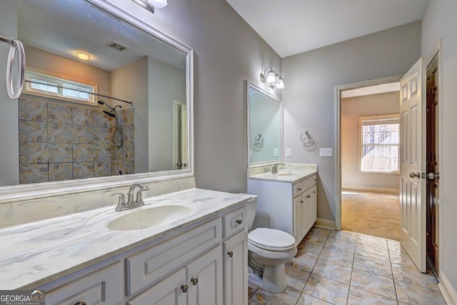 full bath featuring two vanities, visible vents, a sink, and toilet