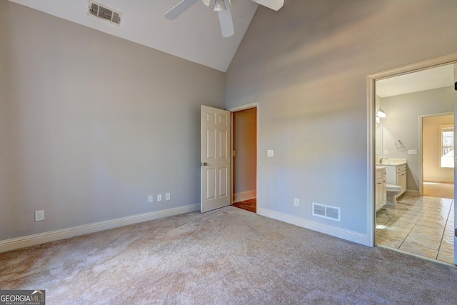 unfurnished bedroom with light carpet, high vaulted ceiling, ensuite bath, and visible vents