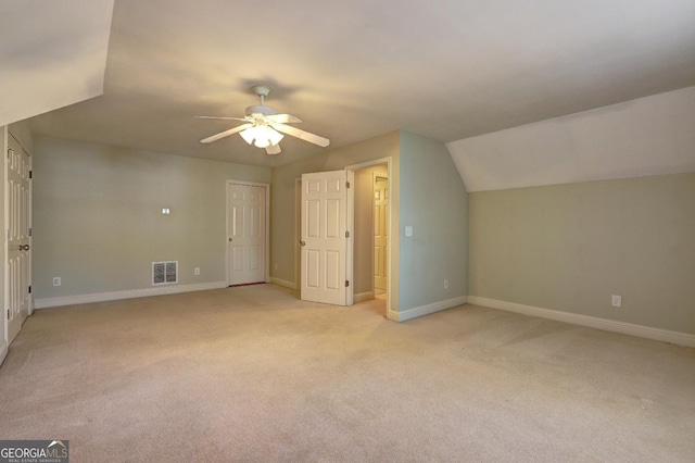 additional living space featuring baseboards, visible vents, a ceiling fan, light colored carpet, and vaulted ceiling