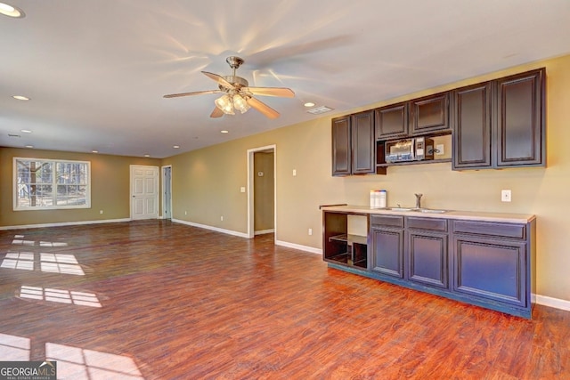 kitchen featuring open floor plan, light countertops, a sink, and wood finished floors