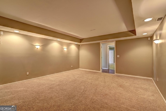 carpeted empty room featuring baseboards, visible vents, a tray ceiling, and recessed lighting