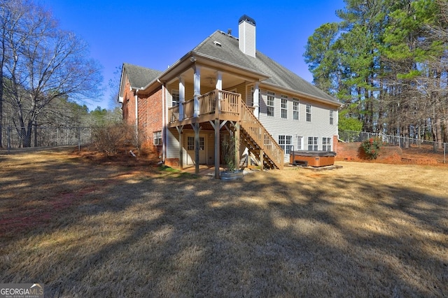 rear view of property with a hot tub, a chimney, stairway, fence private yard, and a wooden deck