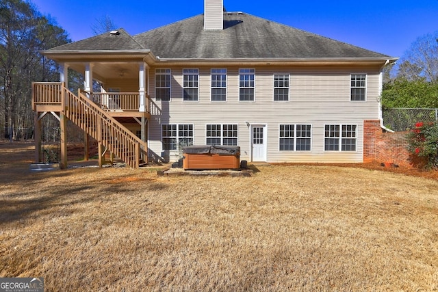 back of house featuring roof with shingles, a yard, a chimney, stairway, and a hot tub