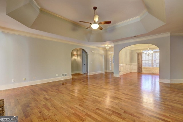 unfurnished room with visible vents, arched walkways, a raised ceiling, light wood-style floors, and ceiling fan with notable chandelier