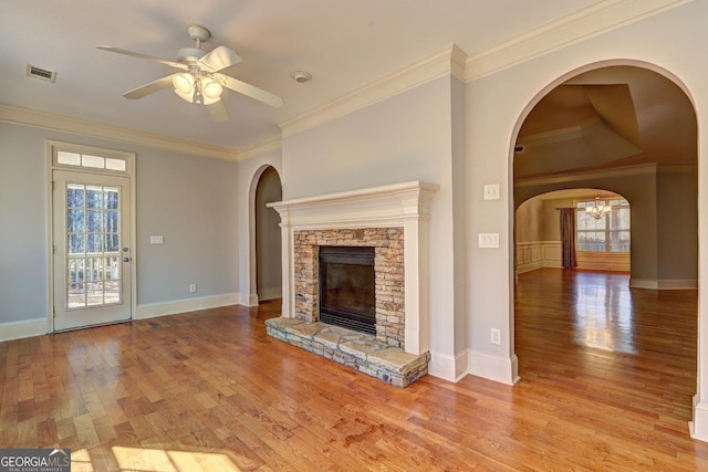 unfurnished living room featuring a fireplace, wood finished floors, visible vents, and crown molding