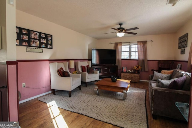 living room with ceiling fan, wood-type flooring, and a textured ceiling