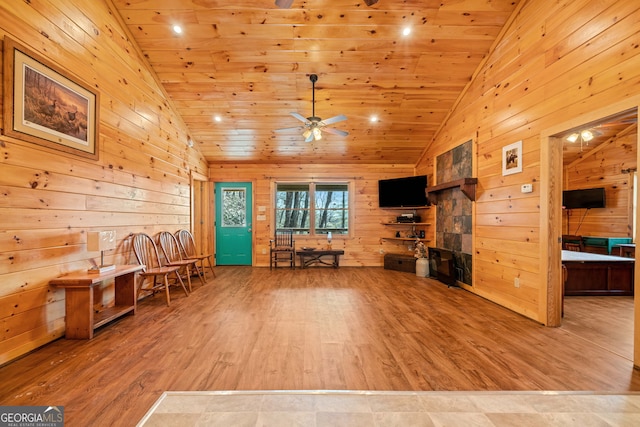 sitting room featuring vaulted ceiling, a ceiling fan, wood finished floors, and wooden walls