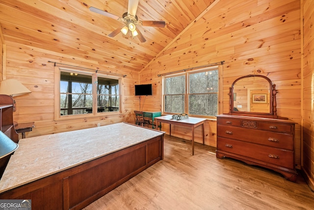 office space with light wood-type flooring, vaulted ceiling, a ceiling fan, wood walls, and wood ceiling