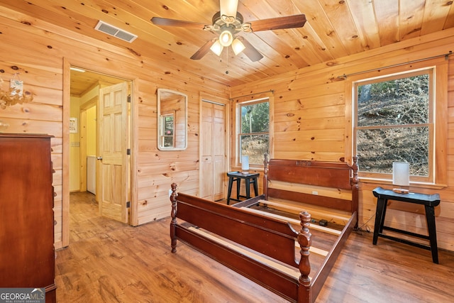 bedroom featuring wooden walls, wood finished floors, visible vents, and wooden ceiling