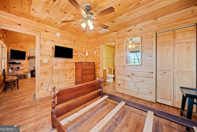 unfurnished bedroom featuring connected bathroom, wooden ceiling, wood finished floors, and wooden walls