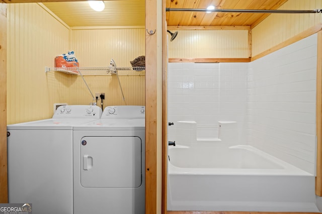 laundry area with wooden ceiling, wooden walls, washer and dryer, and laundry area