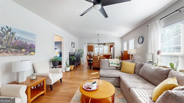 living room with ceiling fan with notable chandelier and light wood-type flooring