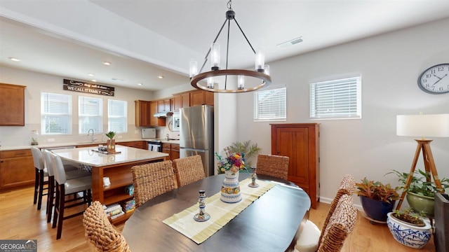 dining space with light hardwood / wood-style flooring, sink, and an inviting chandelier