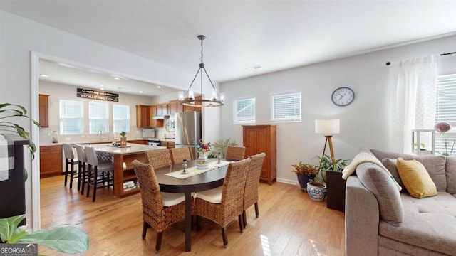 dining room with light hardwood / wood-style flooring, sink, and a chandelier