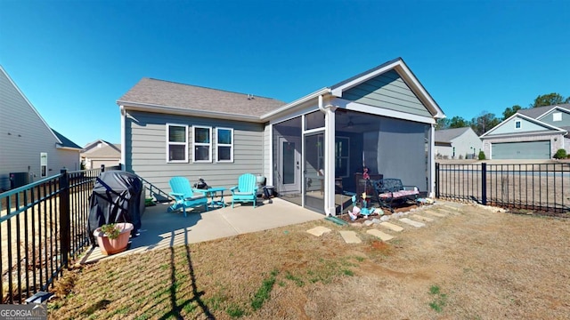 rear view of house featuring a patio, a lawn, and a sunroom