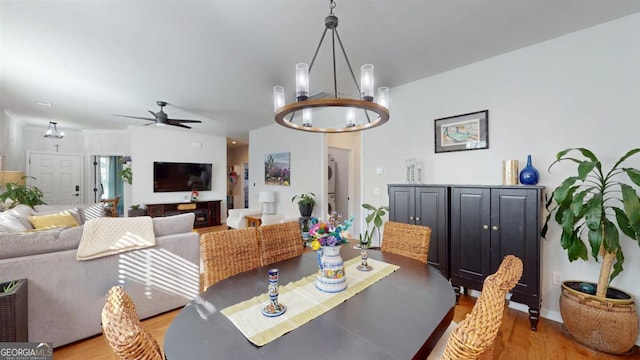 dining area with ceiling fan with notable chandelier and light hardwood / wood-style flooring