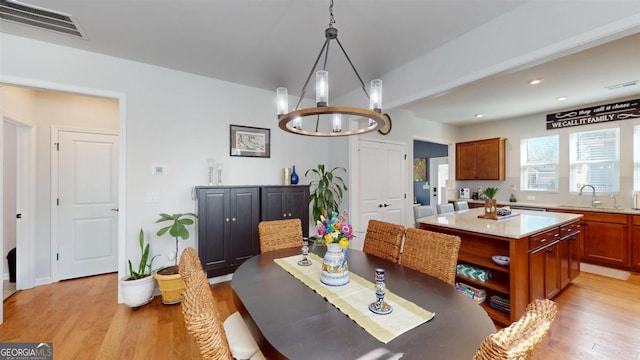 dining space featuring sink, a notable chandelier, and light hardwood / wood-style flooring