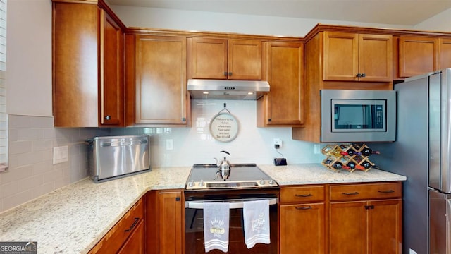 kitchen featuring appliances with stainless steel finishes, tasteful backsplash, and light stone countertops