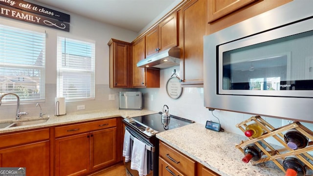 kitchen featuring decorative backsplash, stainless steel appliances, light stone counters, and sink