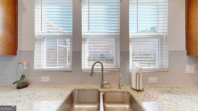 kitchen featuring sink, light stone counters, and a healthy amount of sunlight